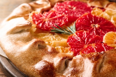 Photo of Tasty galette with citrus fruits and rosemary, closeup