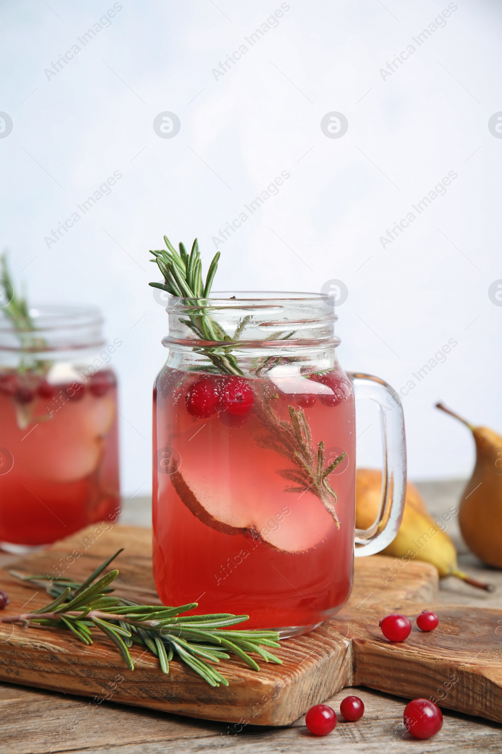 Photo of Tasty refreshing cranberry cocktail with rosemary in mason jars on table