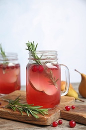 Tasty refreshing cranberry cocktail with rosemary in mason jars on table