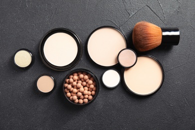 Photo of Flat lay composition with various makeup face powders on dark background