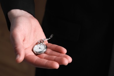 Photo of Man holding chain with elegant pocket watch, closeup