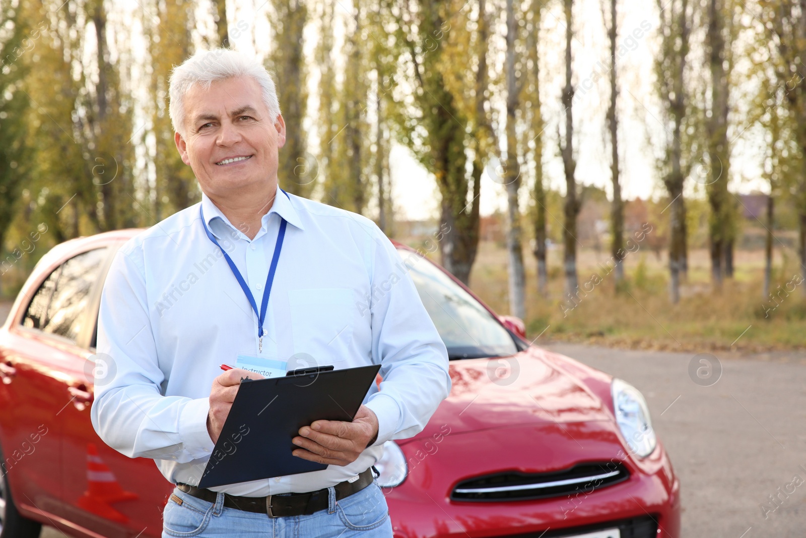 Photo of Senior instructor with clipboard near car outdoors. Get driving license