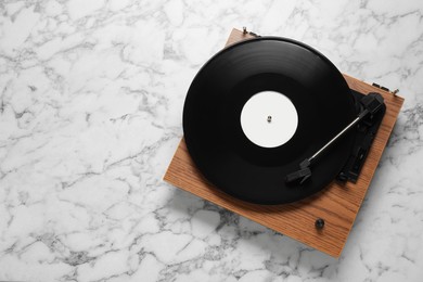 Turntable with vinyl record on white marble background, top view. Space for text