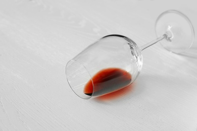 Overturned glass of wine on white wooden background