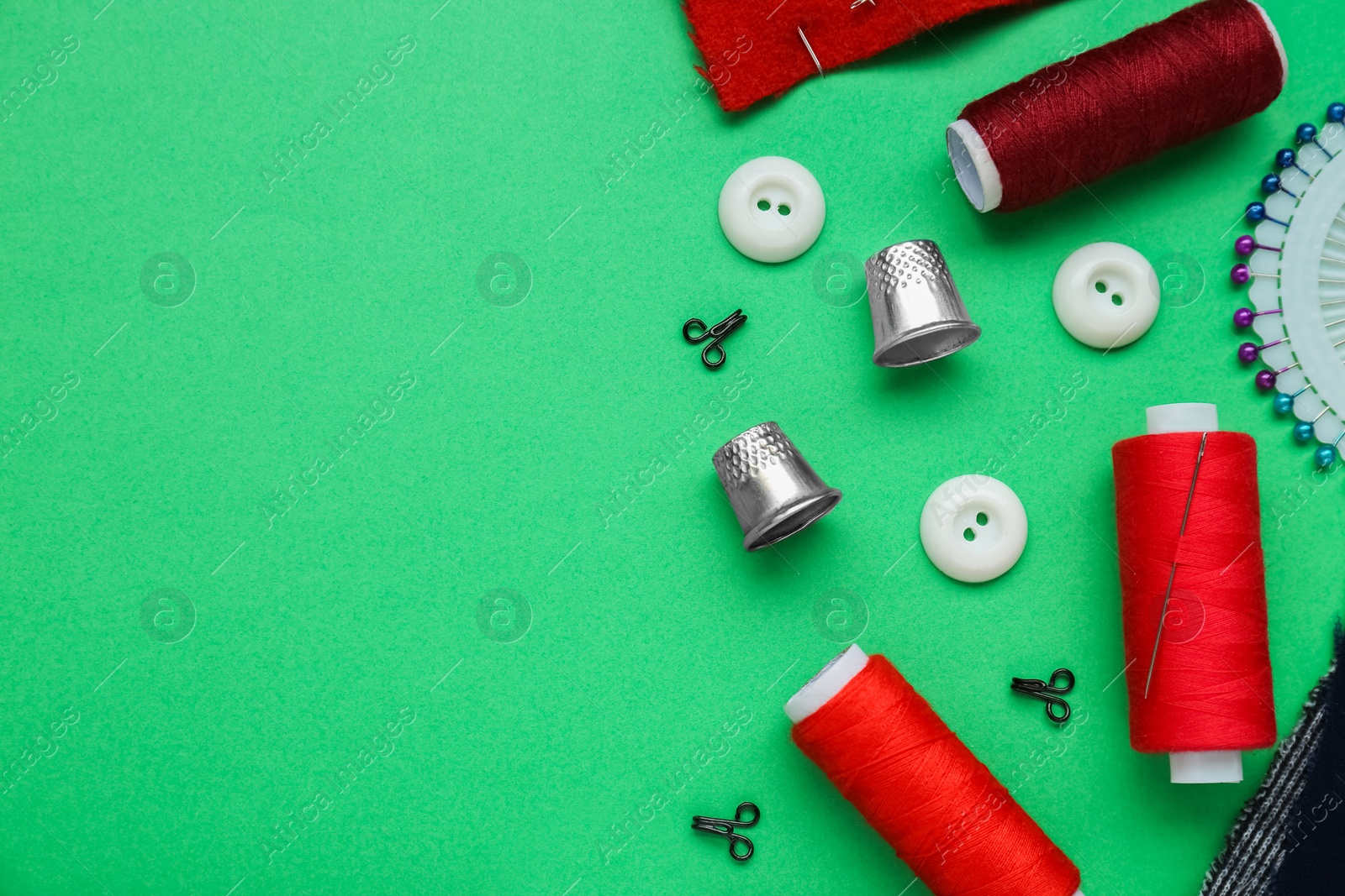 Photo of Flat lay composition with thimbles and different sewing tools on green background. Space for text