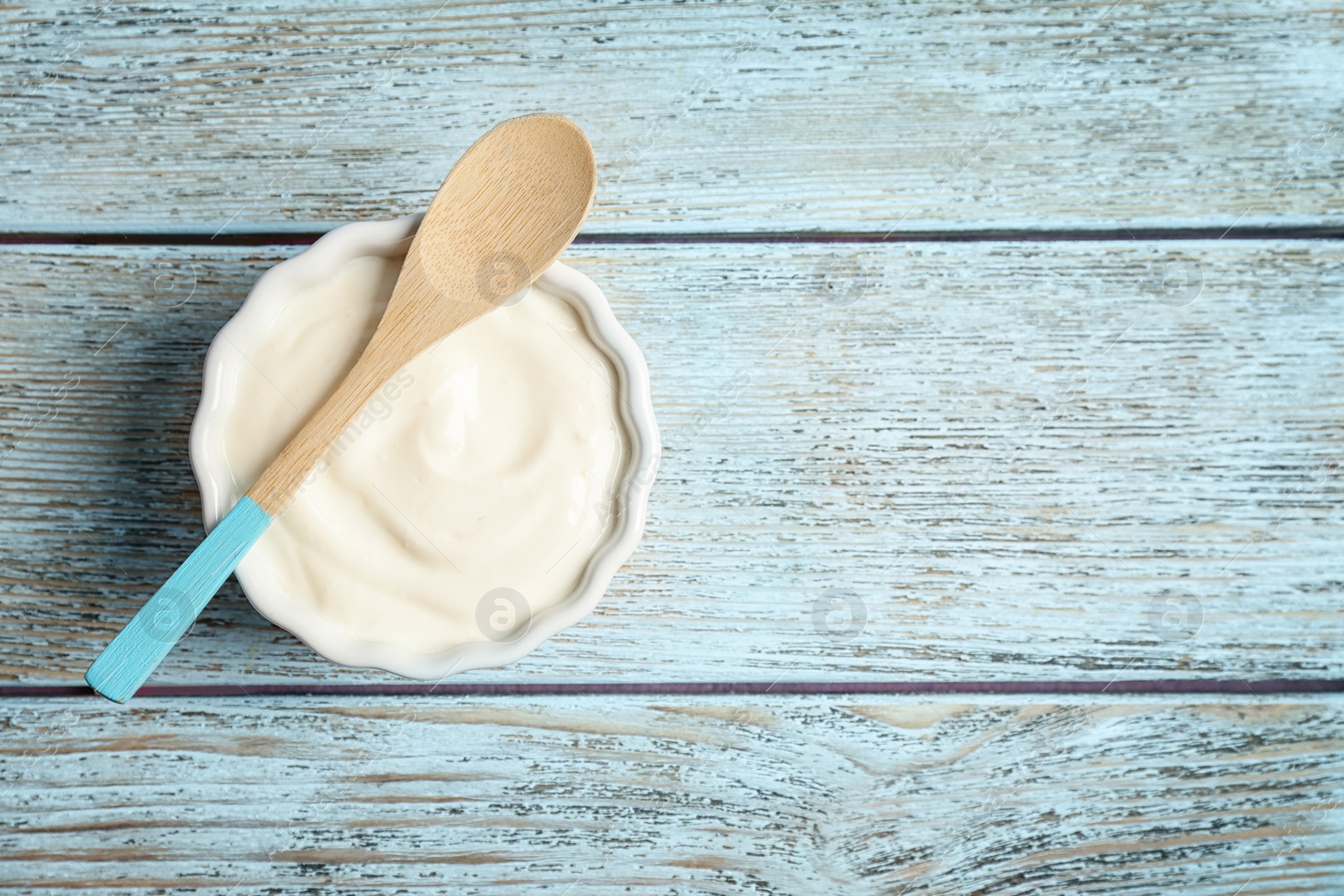 Photo of Bowl with tasty yogurt on wooden background, top view