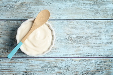 Photo of Bowl with tasty yogurt on wooden background, top view