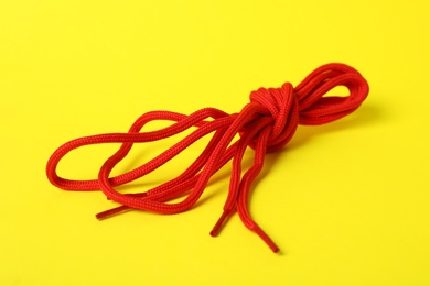 Photo of Red shoe laces tied in knot on yellow background
