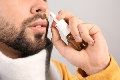 Photo of Man using nasal spray on light grey background, closeup