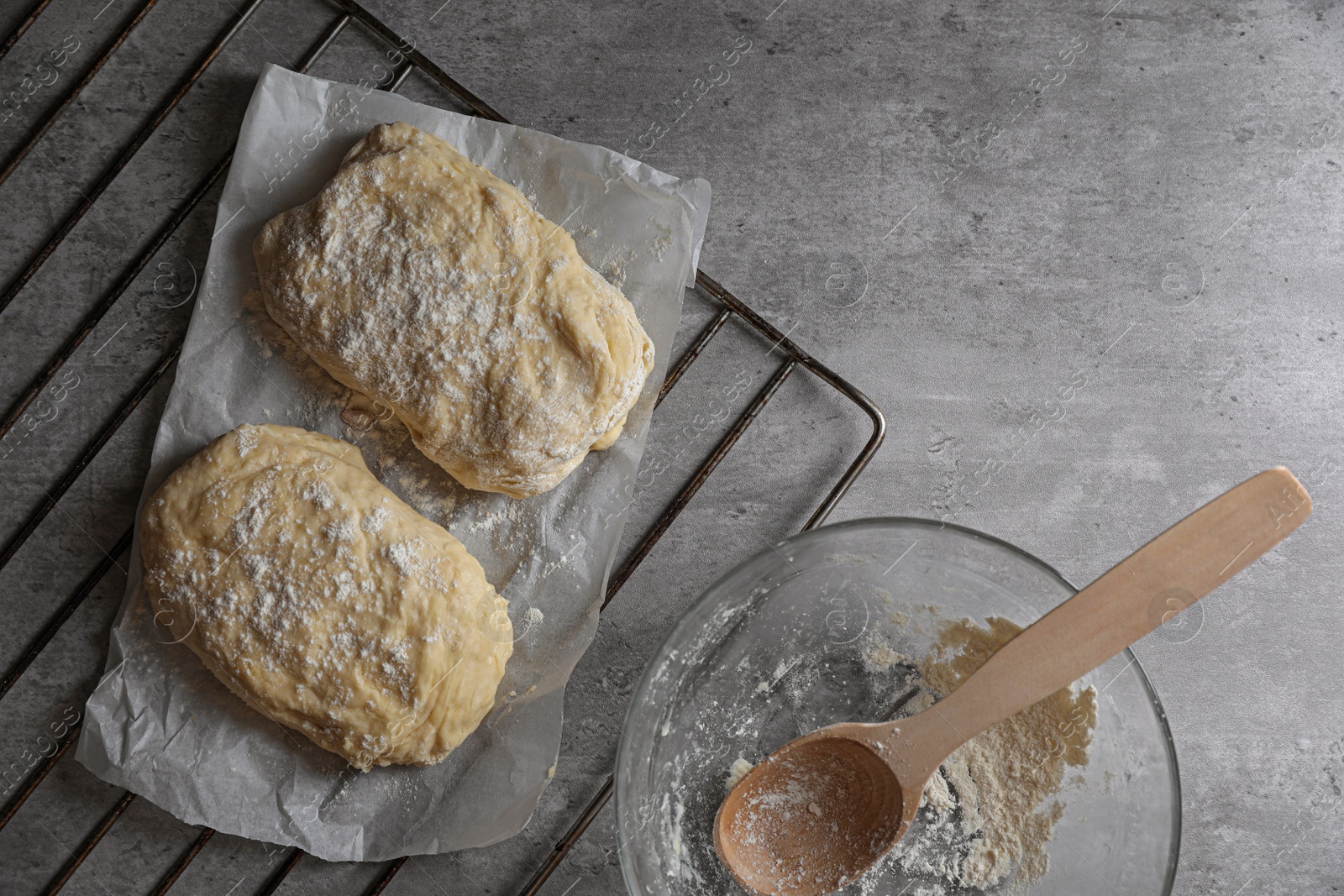 Photo of Raw dough for ciabatta and flour on grey table, flat lay