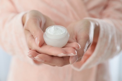 Photo of Young woman holding jar of cream closeup