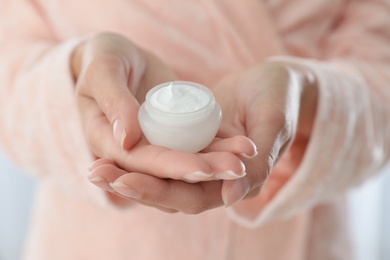 Young woman holding jar of cream closeup