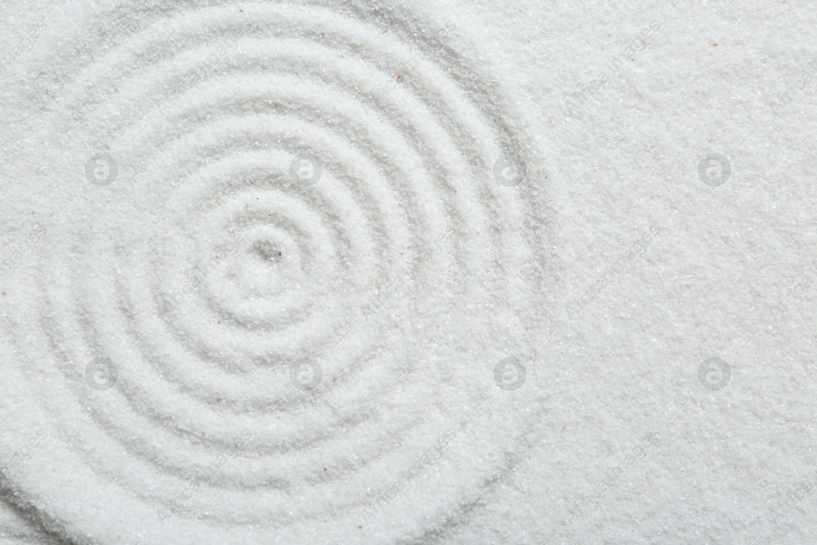 Photo of Zen rock garden. Circle pattern on white sand, top view. Space for text