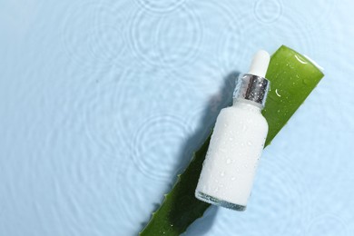 Bottle of cosmetic product and aloe leaf in water on light blue background, flat lay. Space for text