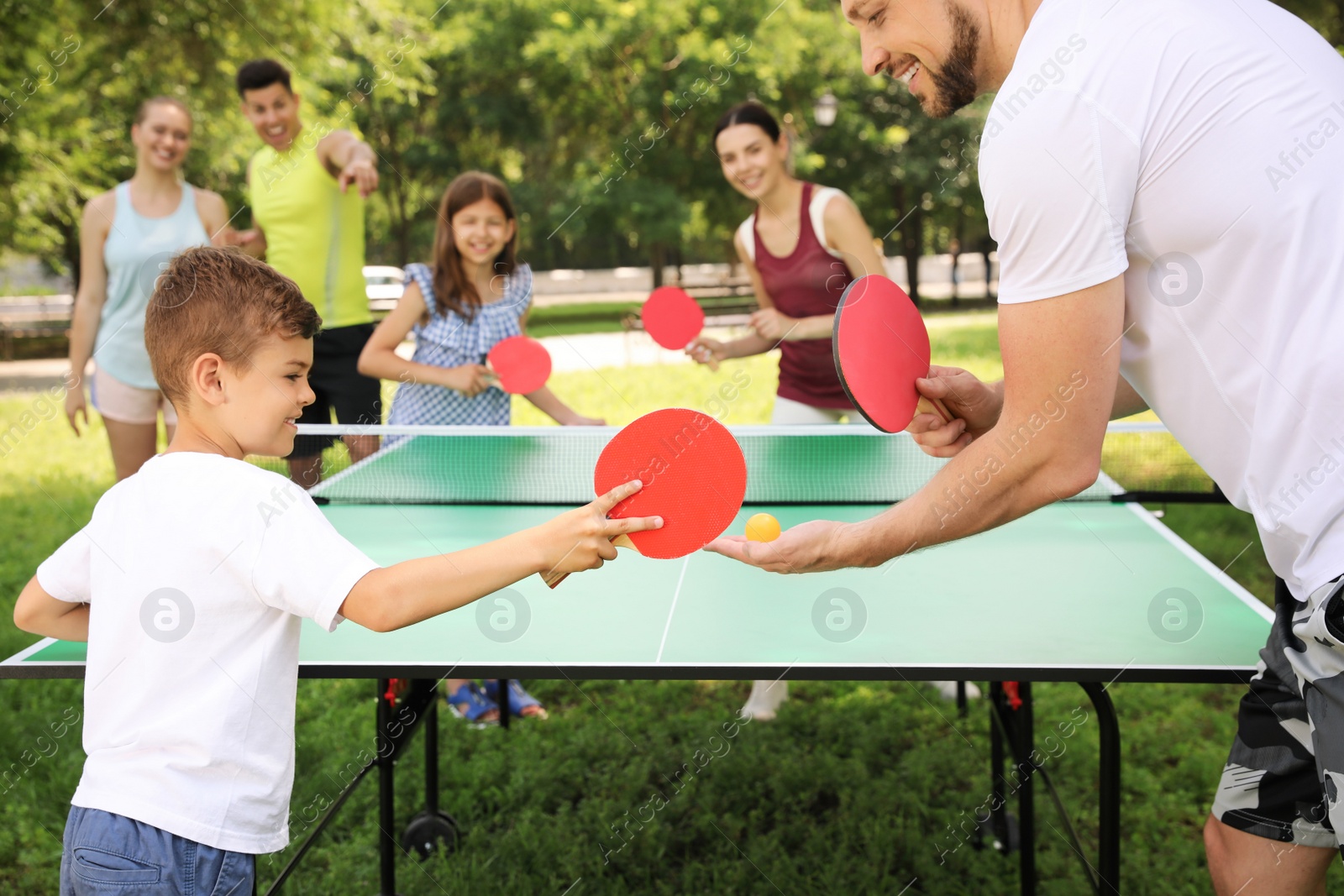 Photo of Happy family playing ping pong in park