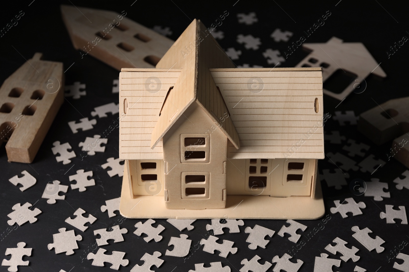 Photo of House model and puzzles on black table depicting destruction after earthquake