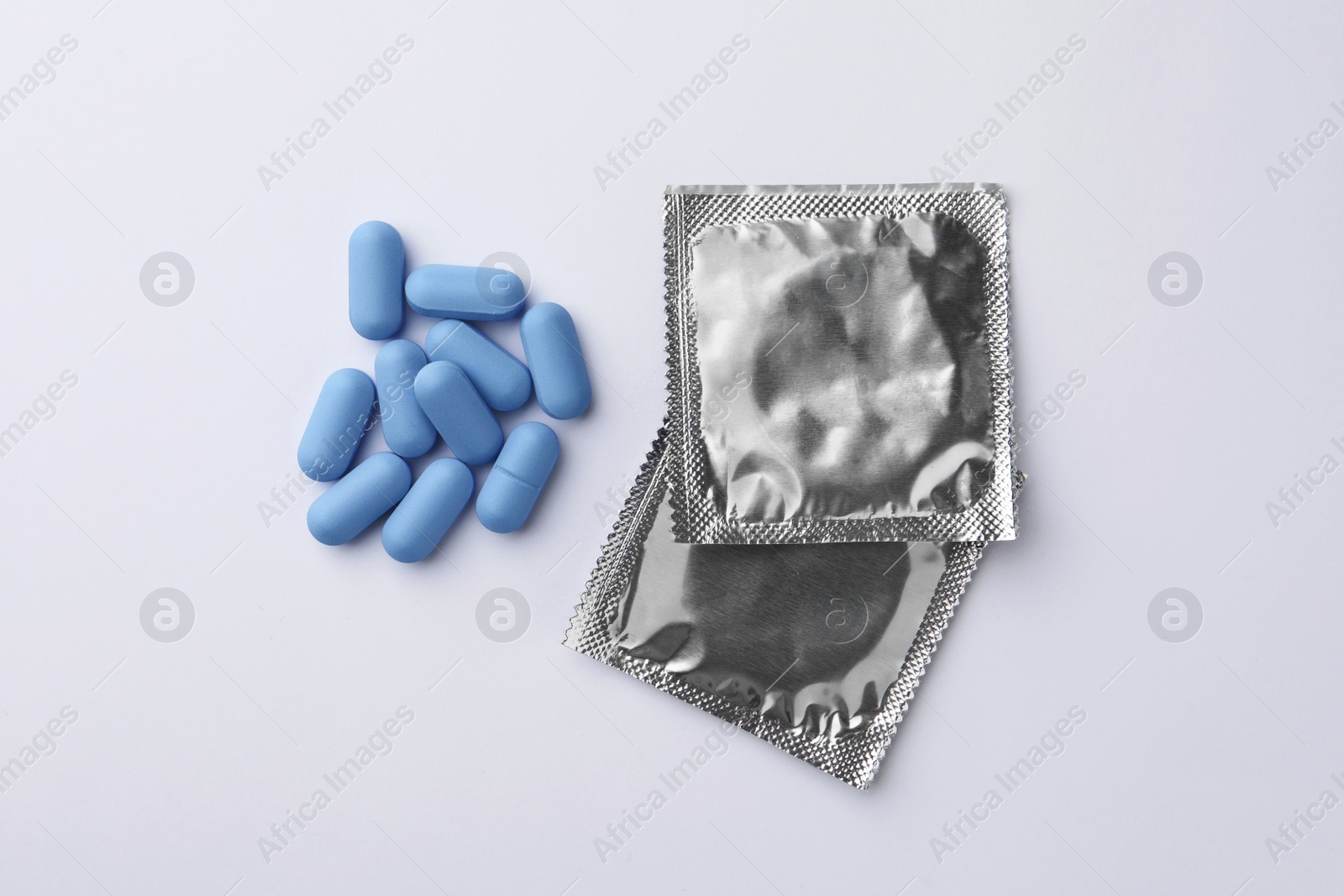 Photo of Pills and condoms on white background, flat lay. Potency problem