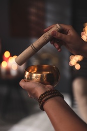 Healer using singing bowl in dark room, closeup