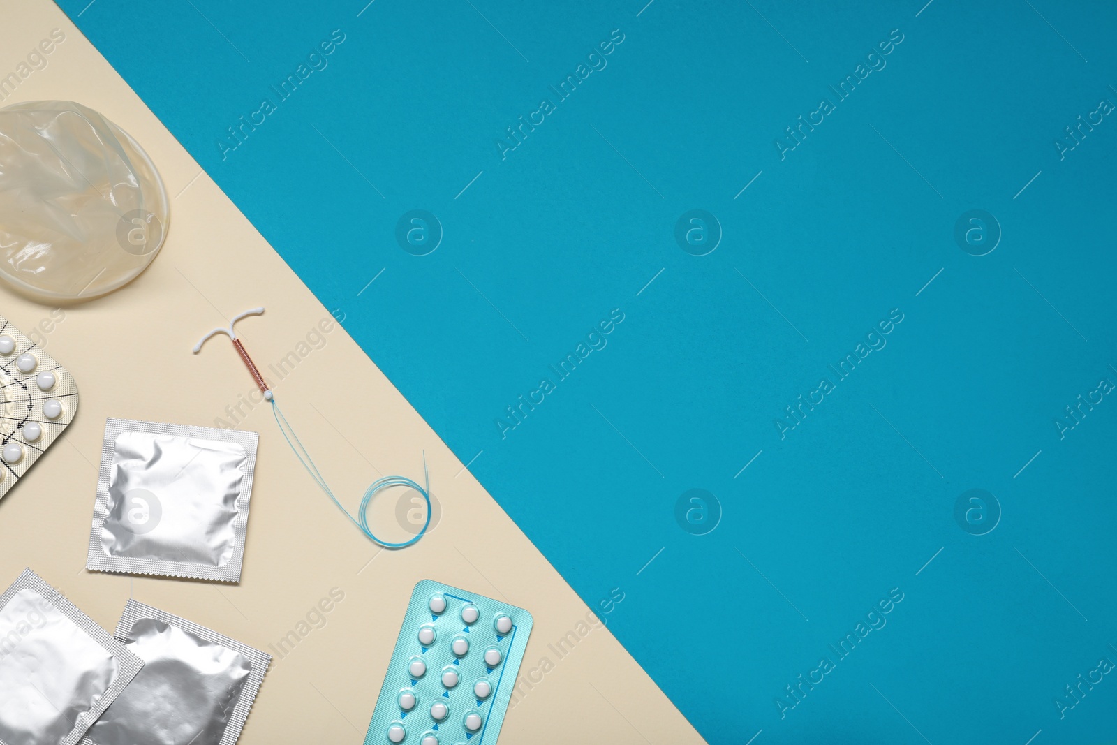 Photo of Contraceptive pills, condoms and intrauterine device on color background, flat lay and space for text. Different birth control methods