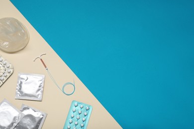 Photo of Contraceptive pills, condoms and intrauterine device on color background, flat lay and space for text. Different birth control methods