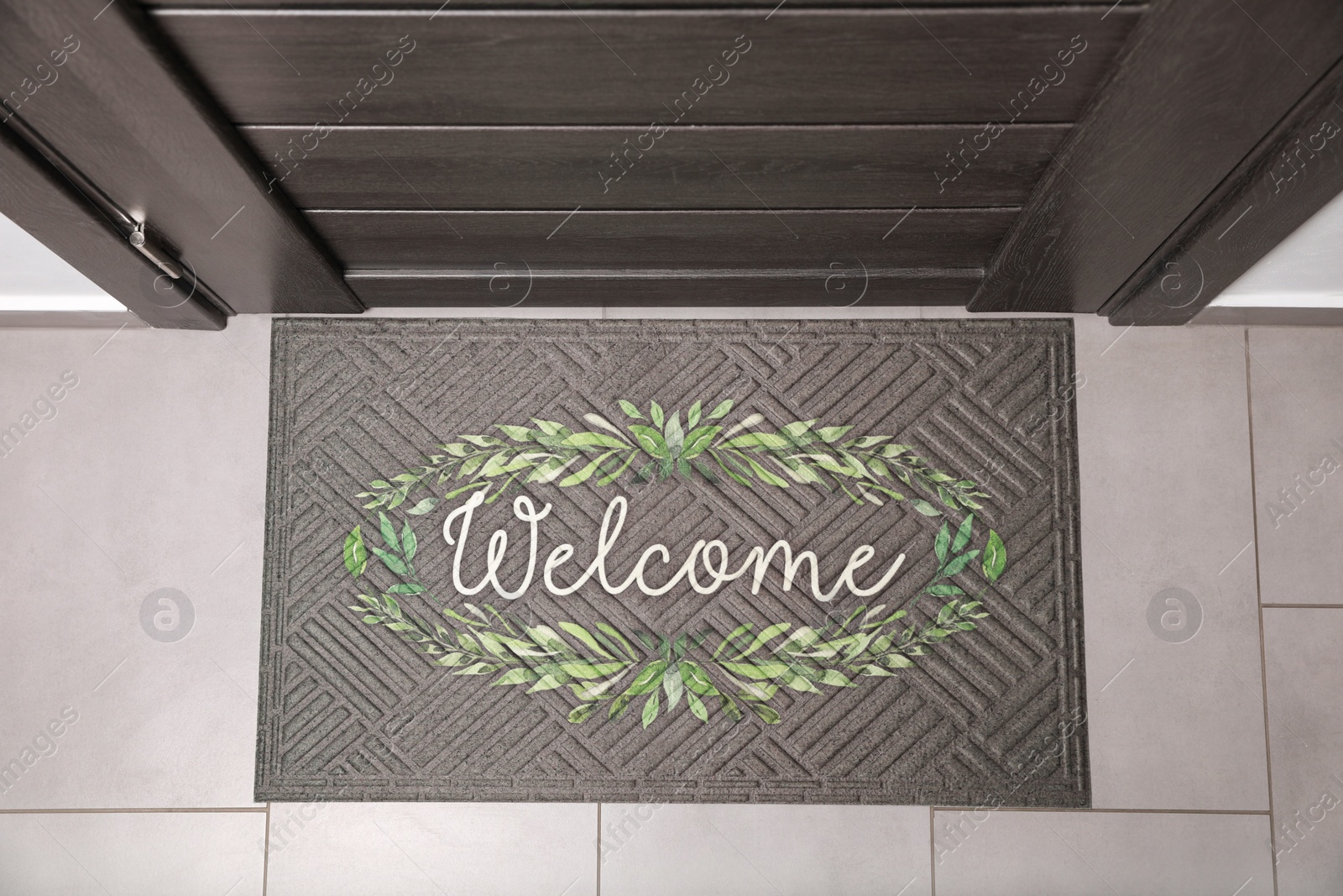 Photo of Beautiful doormat with word Welcome on floor near entrance, top view