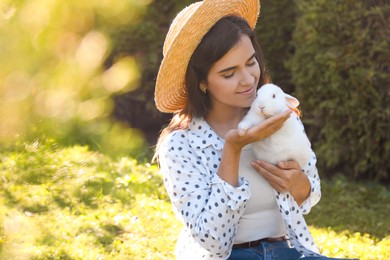 Photo of Happy woman with cute rabbit outdoors on sunny day. Space for text