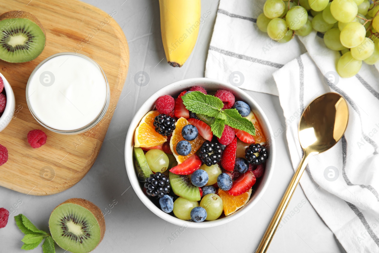 Photo of Fresh tasty fruit salad on grey table, flat lay