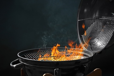 Photo of Modern barbecue grill with burning fire on dark background
