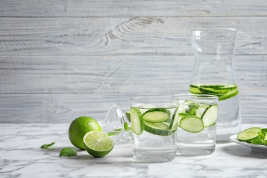 Photo of Glasses with fresh cucumber water on table against light background. Space for text