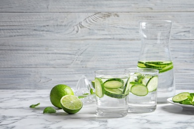 Glasses with fresh cucumber water on table against light background. Space for text