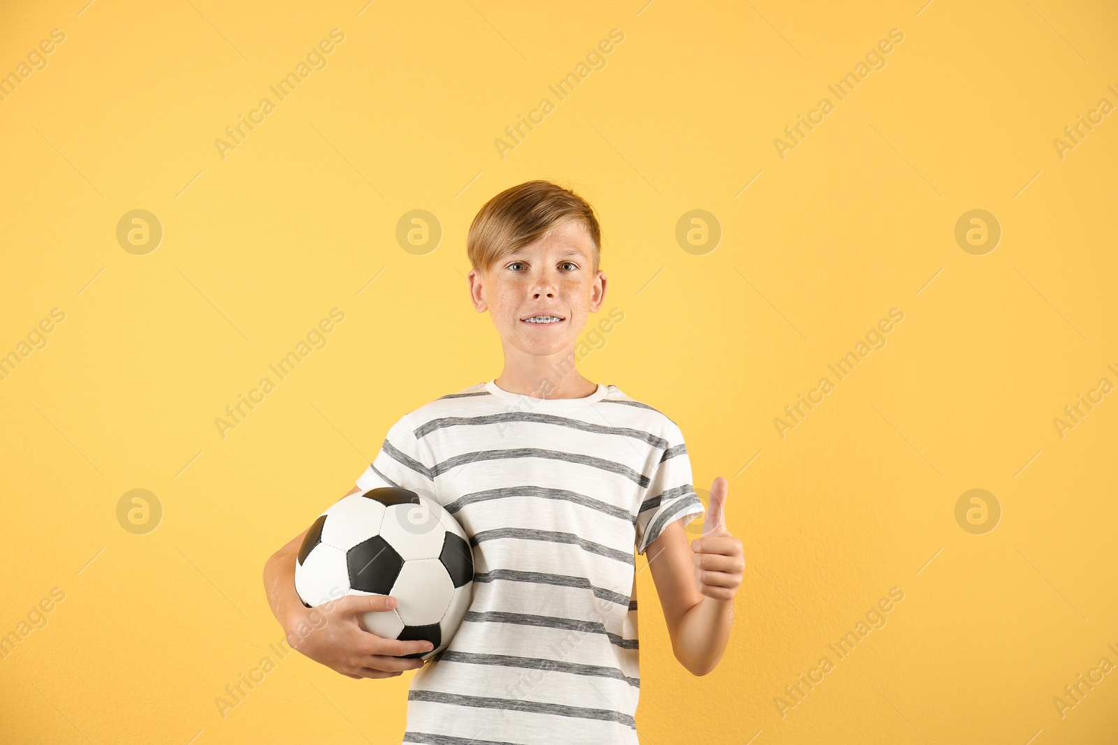 Photo of Portrait of young boy holding soccer ball on color background