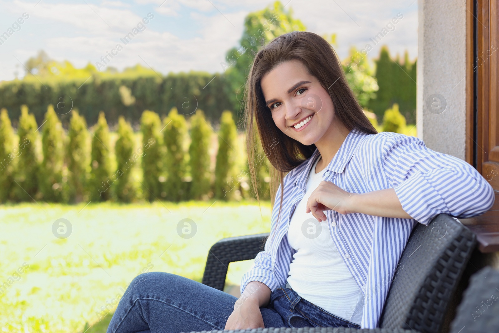 Photo of Portrait of beautiful young woman sitting on chair at backyard, space for text