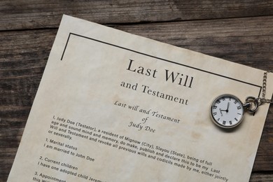 Photo of Last Will and Testament with pocket watch on wooden table, top view