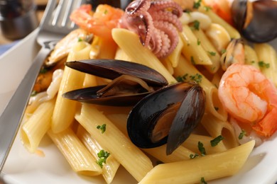 Delicious pasta with seafood and fork on plate, closeup