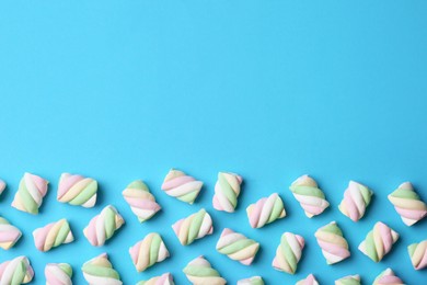 Photo of Delicious colorful marshmallows on light blue background, flat lay. Space for text