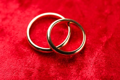 Photo of Honeymoon concept. Two golden rings on red velvet, closeup