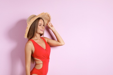 Photo of Sexy young woman in one-piece bathing suit on color background