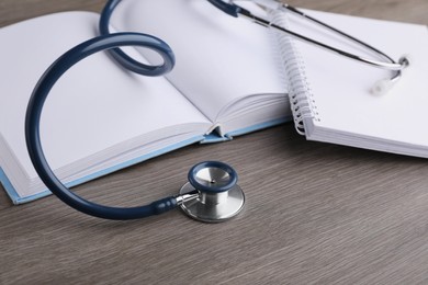Photo of Book, stethoscope and notebook on wooden table. Medical education