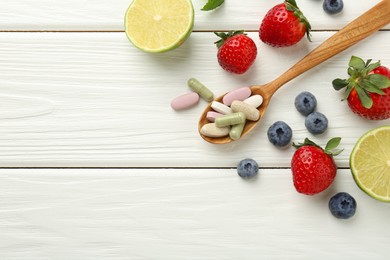 Photo of Different vitamin pills in spoon and fresh fruits on white wooden table, flat lay. Space for text