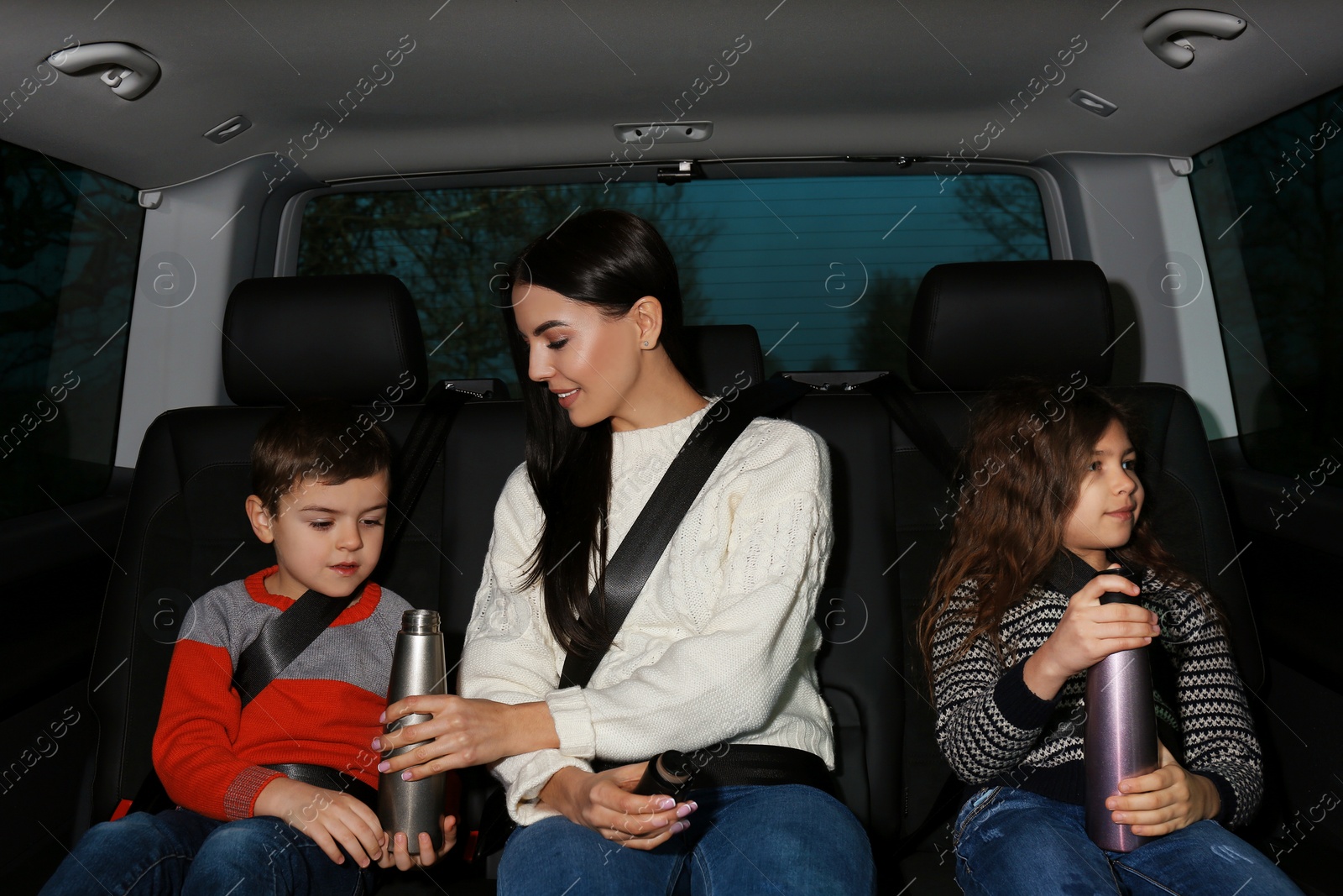 Photo of Mother with little children in modern car. Family trip