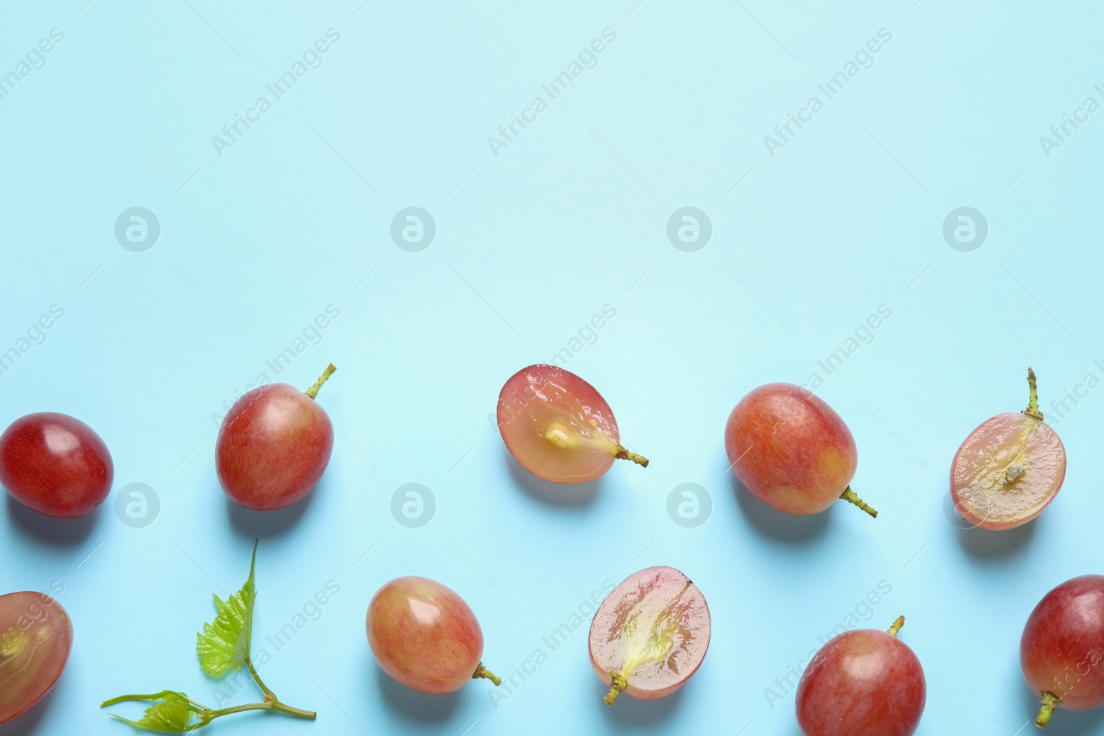 Photo of Flat lay composition with fresh ripe juicy grapes on light blue background, space for text