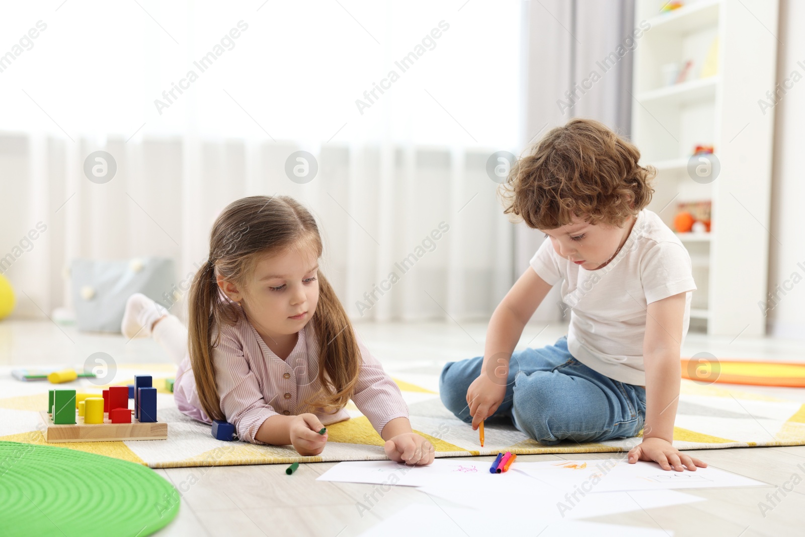 Photo of Cute little children drawing on floor in kindergarten