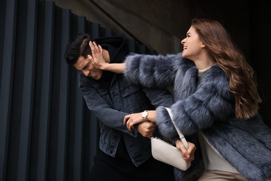 Photo of Woman fighting with thief while he trying to steal her bag in alley. Self defense concept