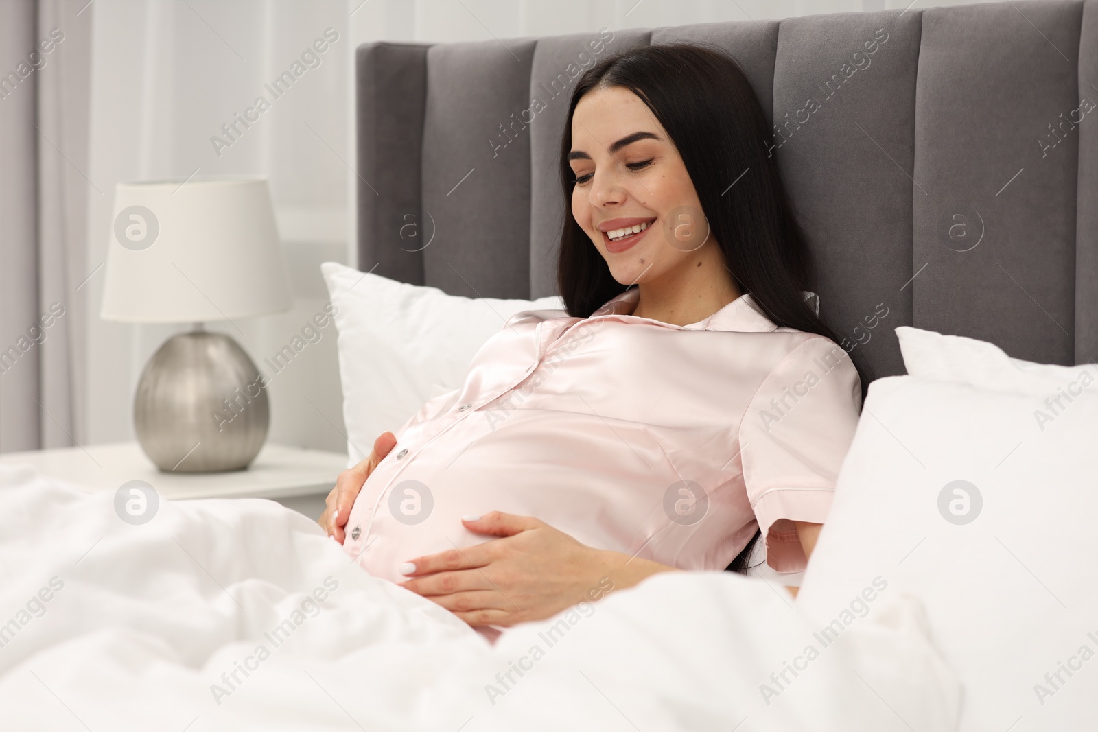 Photo of Happy pregnant woman in bed at home