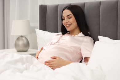 Photo of Happy pregnant woman in bed at home