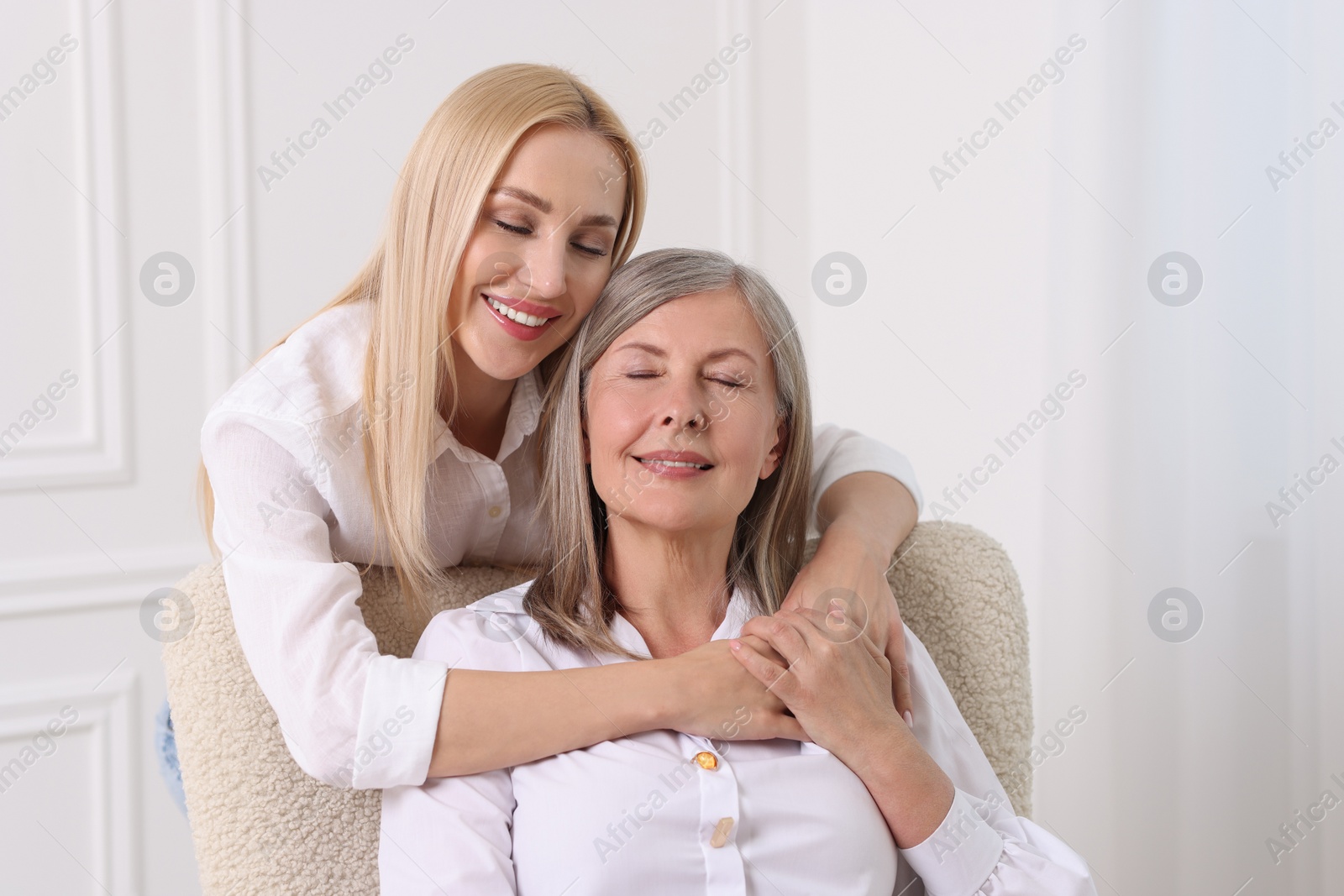 Photo of Family portrait of young woman and her mother near white wall