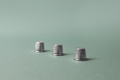 Photo of Three thimbles on pale olive background. Thimblerig game