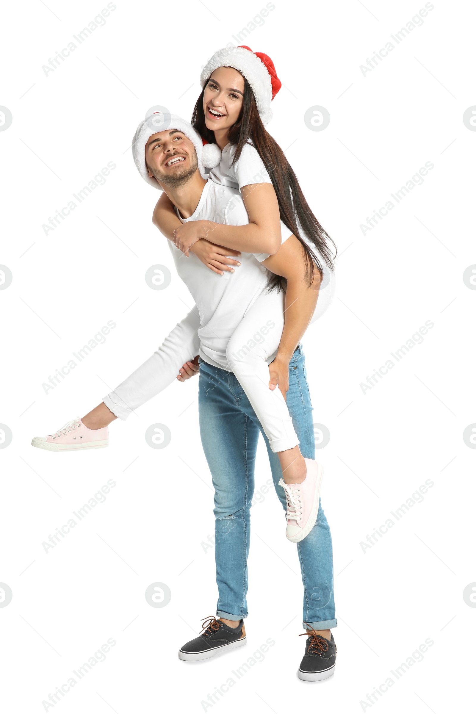 Photo of Young happy couple with Santa hats on white background. Christmas celebration