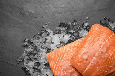 Photo of Fresh raw salmon with ice on black table, flat lay. Space for text