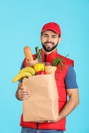 Photo of Man holding paper bag with fresh products on color background. Food delivery service